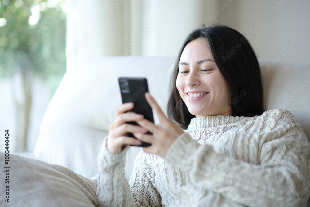 Woman in sweater checking cell phone at home Woman in sweater checking cell phone at home