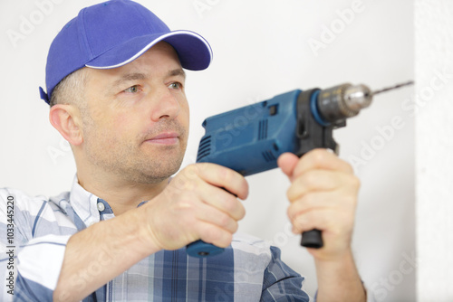 building worker with perforator drilling the wall indoors