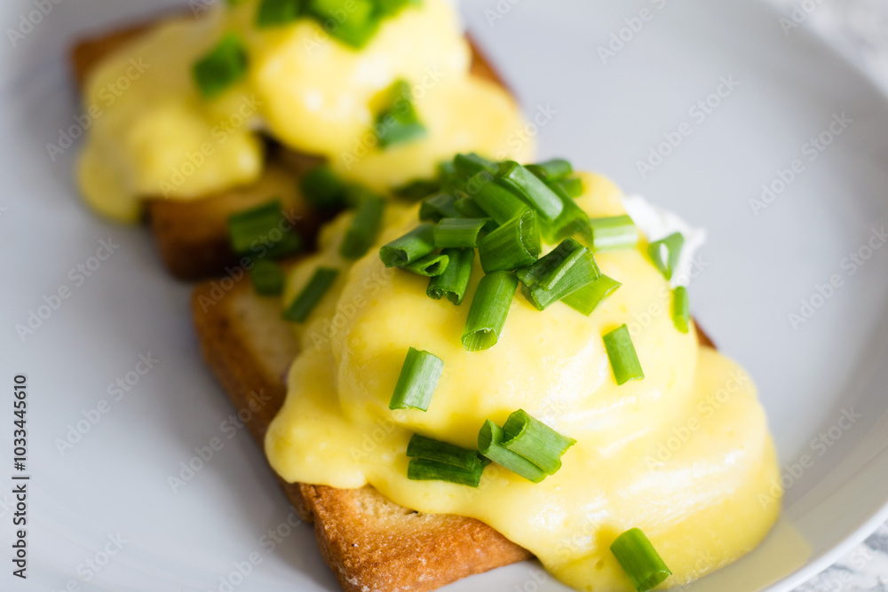 Delicious English breakfast. Eggs benedict with sauce and bacon on toasted white bread on a gray plate, close-up on a light background Delicious English breakfast. Eggs benedict with sauce and bacon on toasted white bread on a gray plate, close-up on a light background