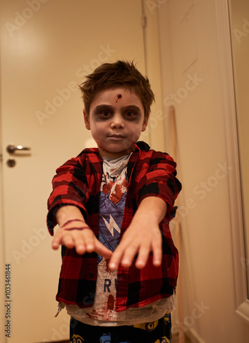 Sinister or scaring child pretends to be a zombie shot in the head as Halloween costume. Scary kid dressed as a Halloween demon or dead spectre ready for trick or treat. Death and apocalypse concept