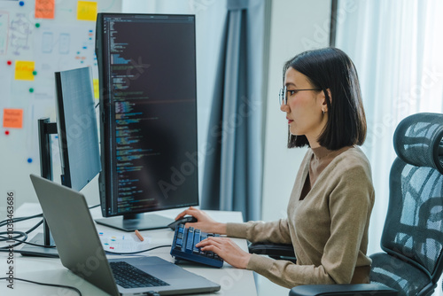 Asian prompt engineer develop coding app with software data sitting in front of computer monitor at office