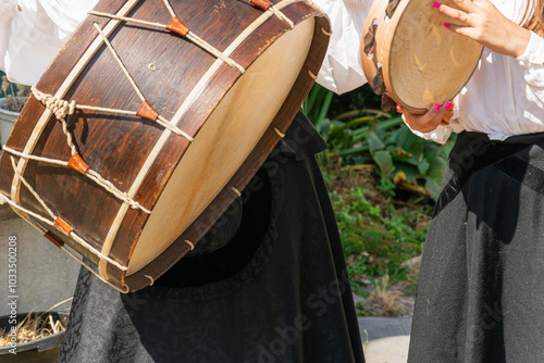 two women musicians playing a bass drum and tambourine at a folkloric event in Galicia, Spain.