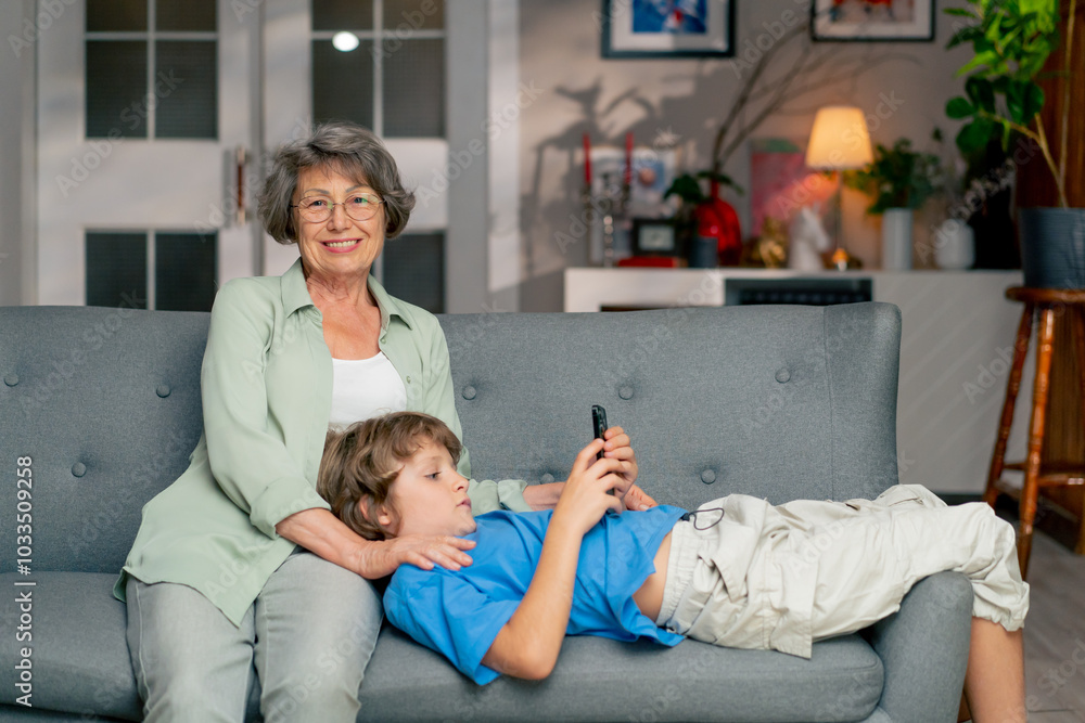 bright living room with sofa grandmother sitting on sofa grandson lying and watching cartoons on tablet happy family bright living room with sofa grandmother sitting on sofa grandson lying and watching cartoons on tablet happy family