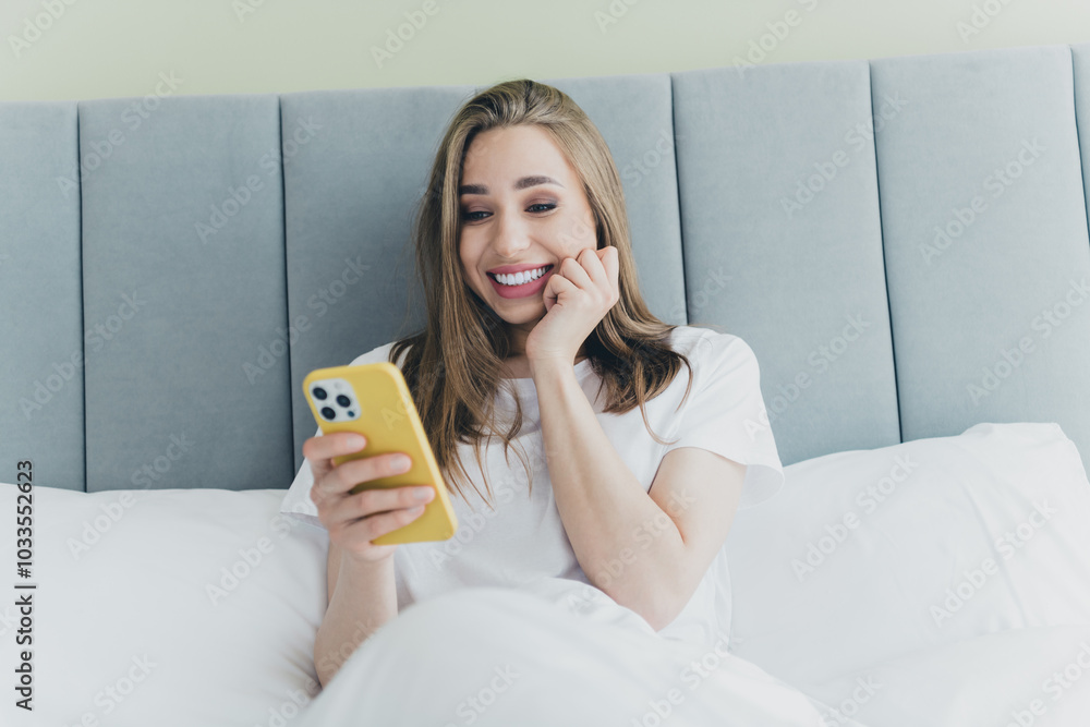 Photo of shiny excited girl nightwear smiling enjoying lying bed typing modern device indoors house apartment room Photo of shiny excited girl nightwear smiling enjoying lying bed typing modern device indoors house apartment room