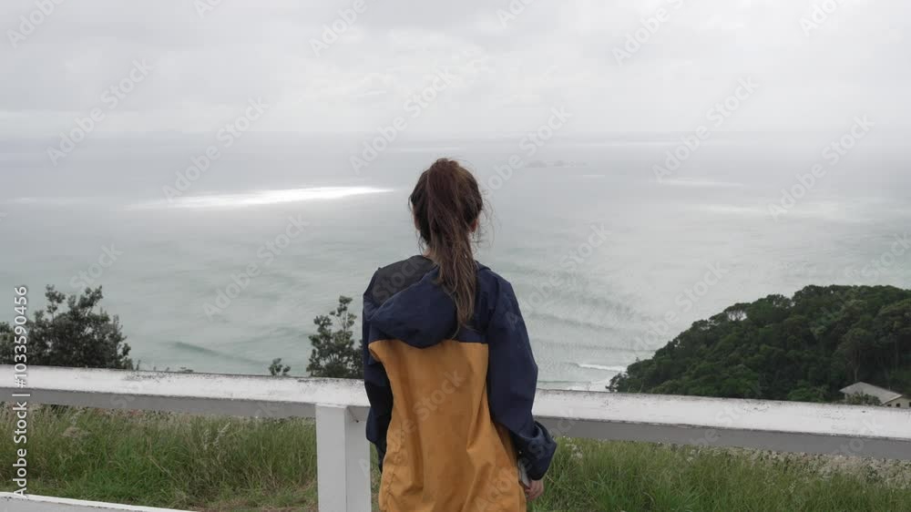 Looking at ocean waves, young brunette woman overlooking relaxing landscape Looking at ocean waves, young brunette woman overlooking relaxing landscape