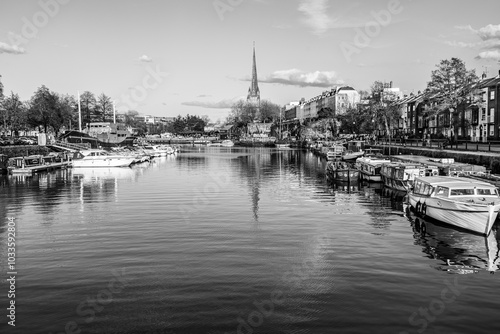 Bristol, England, UK - April 2023: The gothic church of Saint Mary Redcliffe on the shores of river Avon with boats docked in the harbor in black and white photo