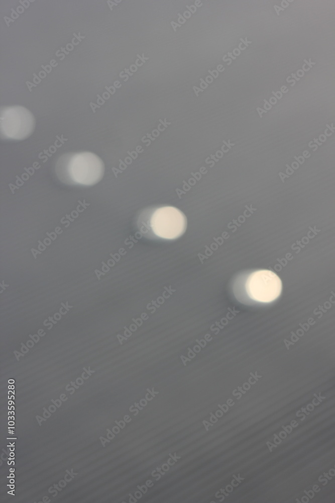 A blurry dreamy view of white lights shining on the gray background. A blurry dreamy view of white lights shining on the gray background.