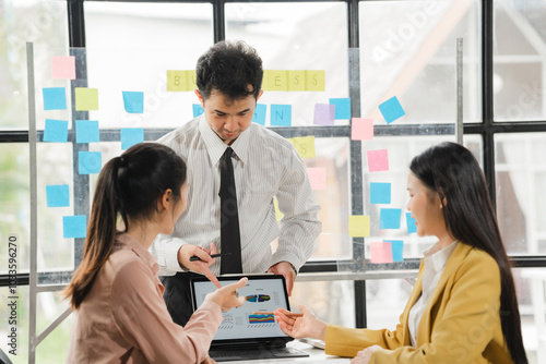 Teamwork Makes the Dream Work: Business colleagues collaborate on a project, using a tablet to review data and sticky notes for brainstorming.