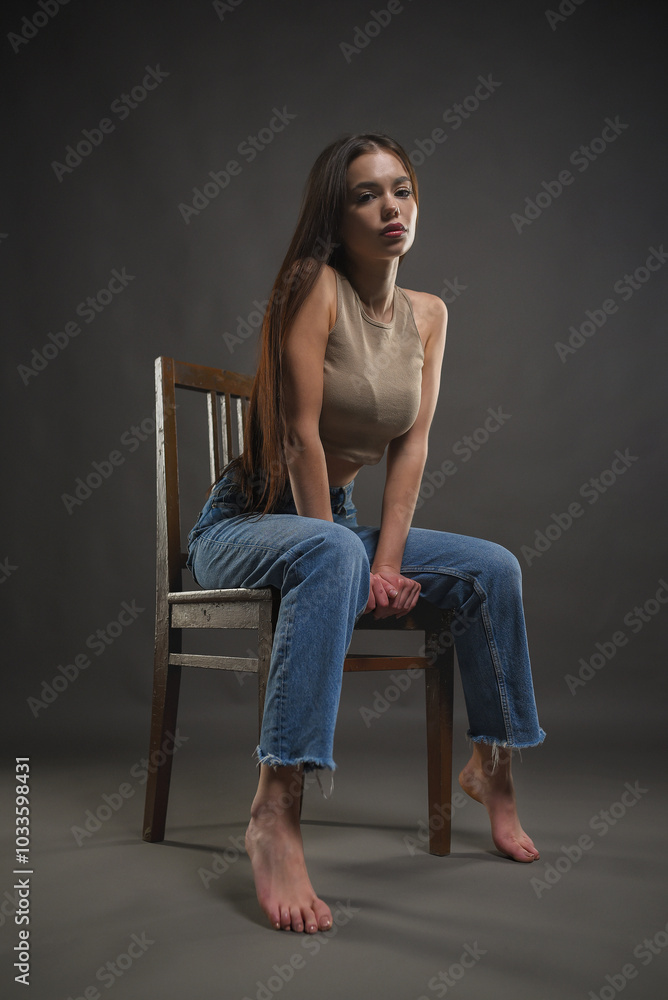 Naklejka premium Beautiful girl posing with a chair on a gray background. Beauty and fashion.