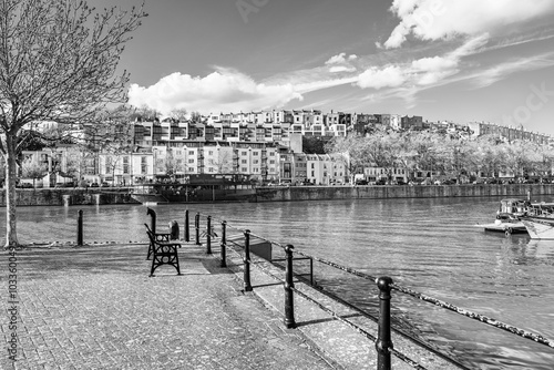 Bristol, England, UK - April 2023: Black and white houses on the waterfront of the river Avon in Bristol Marina; bench by the river