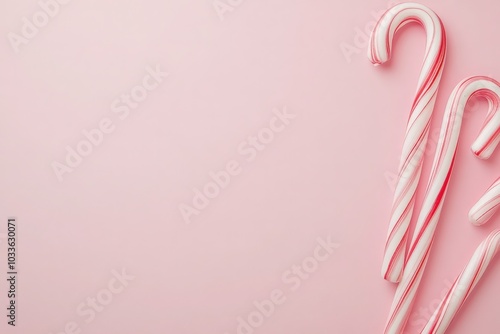 Festively colored candy canes rest elegantly on a smooth pastel background, embodying the spirit of the holiday season. Their vibrant red and white stripes add a cheerful touch to any decor.