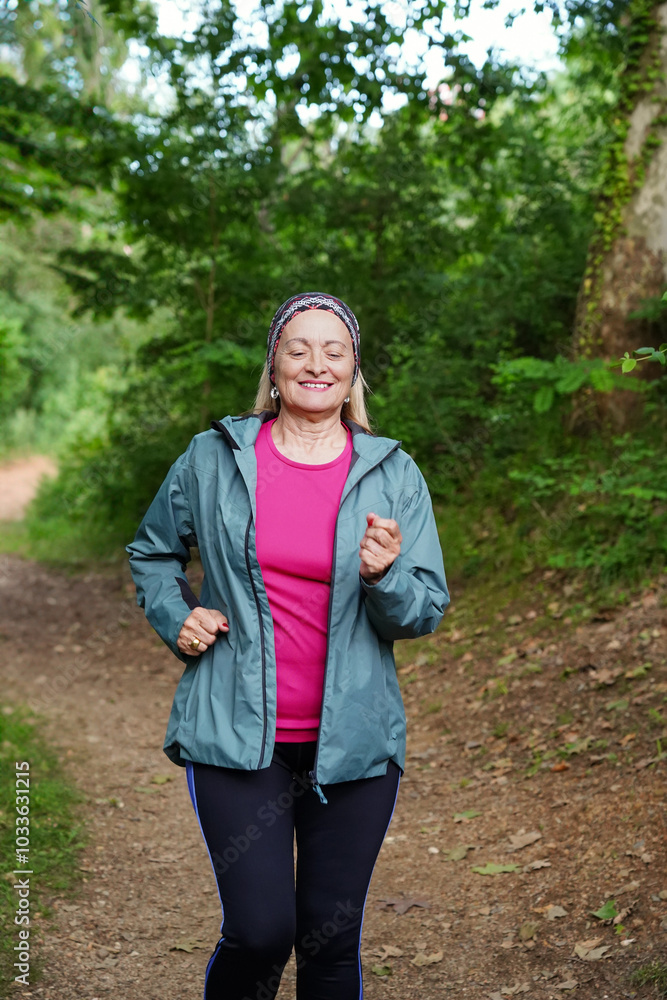 Senior woman jogging in a green forest trail Senior woman jogging in a green forest trail