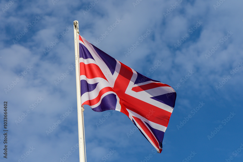 Union Jack flag waving against a bright blue sky during a sunny day in the United Kingdom showcasing national pride and identity Union Jack flag waving against a bright blue sky during a sunny day in the United Kingdom showcasing national pride and identity