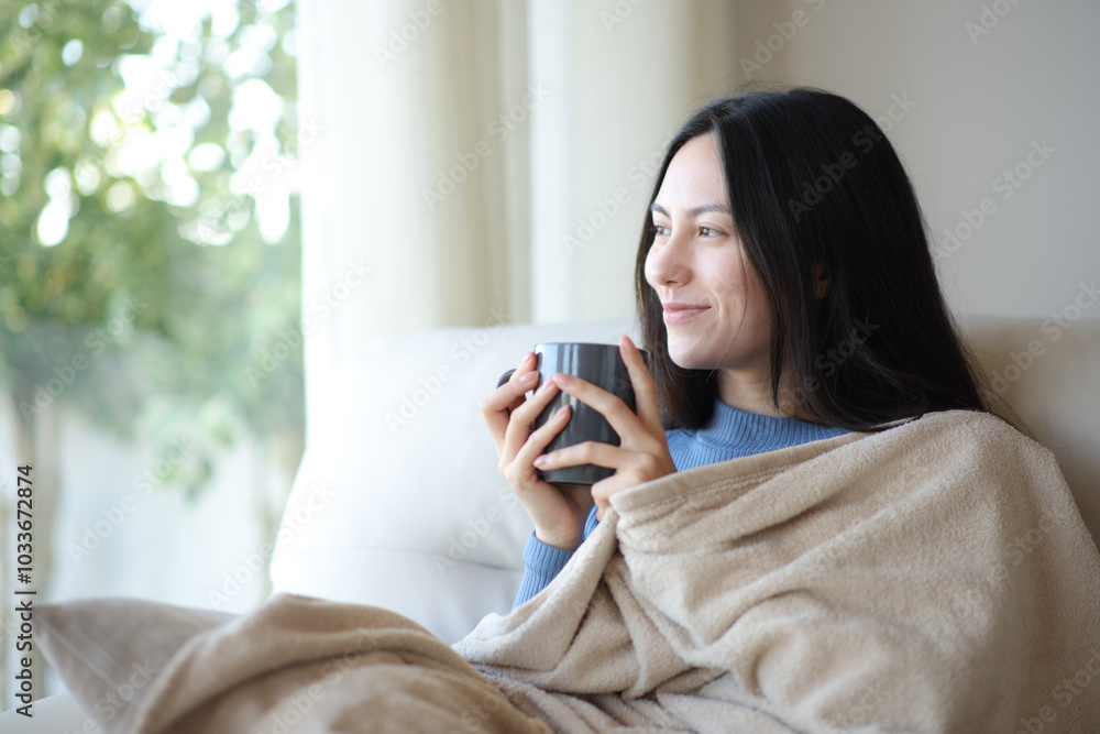 Relaxed asian woman looking through a window keeping warm Relaxed asian woman looking through a window keeping warm
