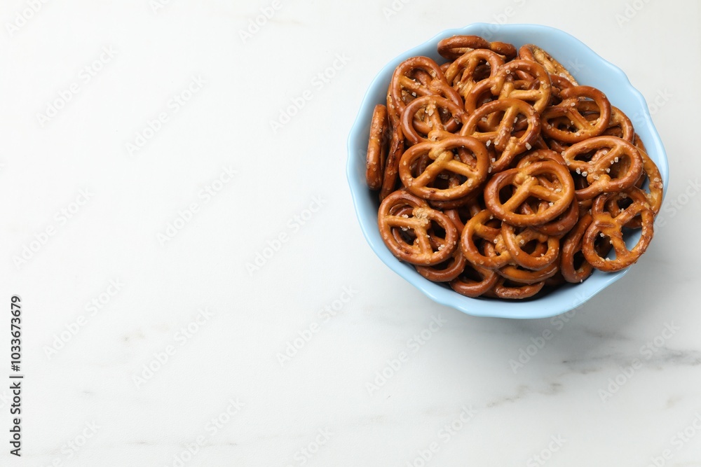 Tasty pretzel crackers in bowl on white marble table, top view. Space for text Tasty pretzel crackers in bowl on white marble table, top view. Space for text