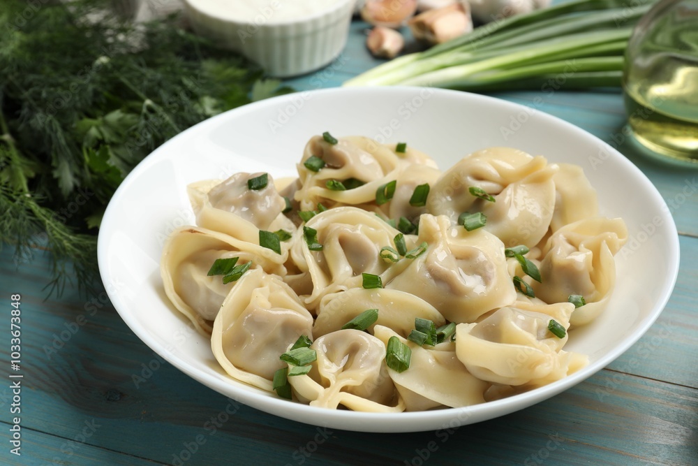 Delicious pelmeni with green onion served on blue wooden table, closeup Delicious pelmeni with green onion served on blue wooden table, closeup