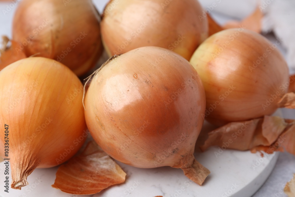 Fresh onions with peels on light table, closeup