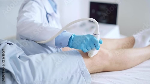 Doctor woman wearing blue medical gloves performing knee ultrasound exam on male patient with shorts . Medicine, orthopedic service concept photo