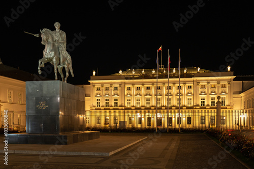 Night view of Warsaw's Presidential Palace illuminated, with equestrian statue of Prince Józef Poniatowski in foreground. Historic architecture and national symbols of Poland's capital.