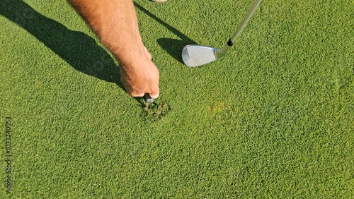 A golfer repairs the greens at a single golf course in the afternoon, paying special attention to keeping the putting