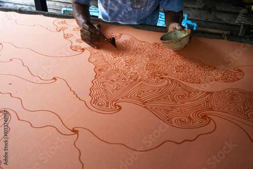 Craftsmanship of thai professional artist working use Tjanting tool or canting equipment and beeswax drawing batik ikat in handmade studio handicrafts workshop at Pak Bara of La ngu in Satun, Thailand photo