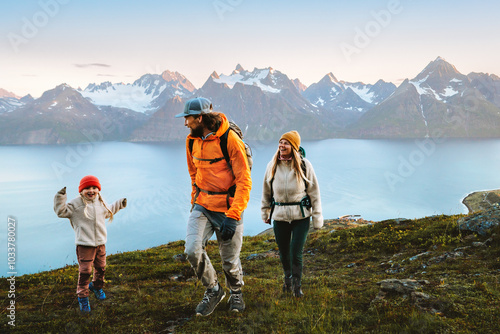 Family travelers hiking together - mother, father, and kid on active vacations in mountains of Norway, parents and child having fun outdoor, healthy lifestyle tourism adventure trip in Lyngen Alps