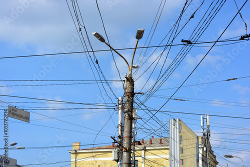 Architecture, unusual places. Electricity, electrical wiring, electrical engineering. Many black power lines hang on a concrete pole in the city of Dnipro, Dnipropetrovsk, Ukraine. photo