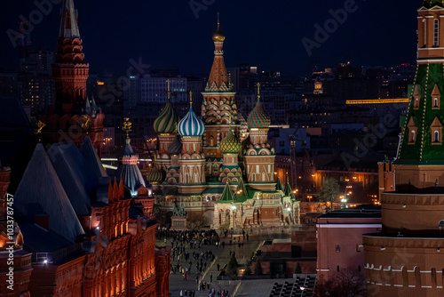Top view of St. Basil's Cathedral in Moscow at night, with its vibrant domes illuminated, surrounded by historic buildings and the Kremlin towers under a on a spring evening, Russia