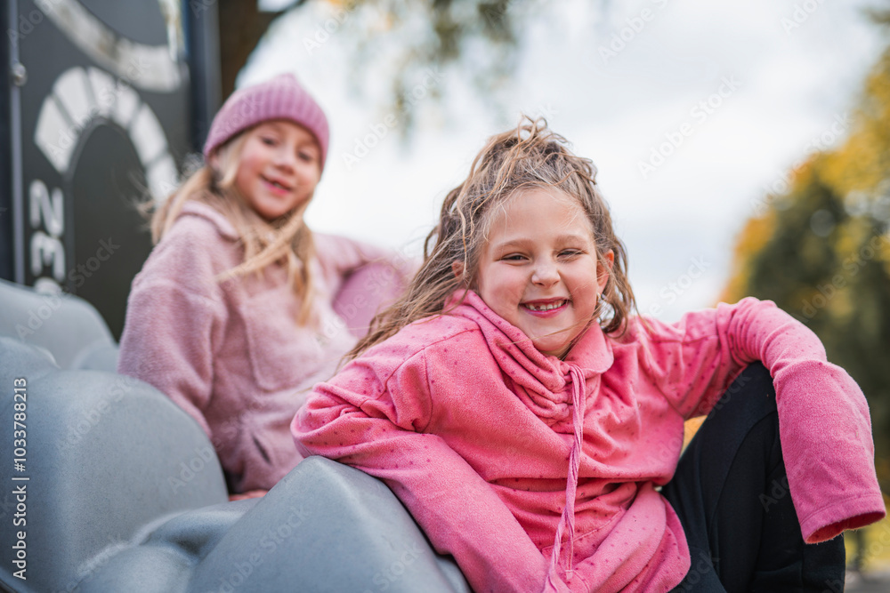 two Little girls having fun on a playground in public park on autumn day. two Little girls having fun on a playground in public park on autumn day.
