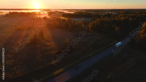 A truck is driving along the road at sunset