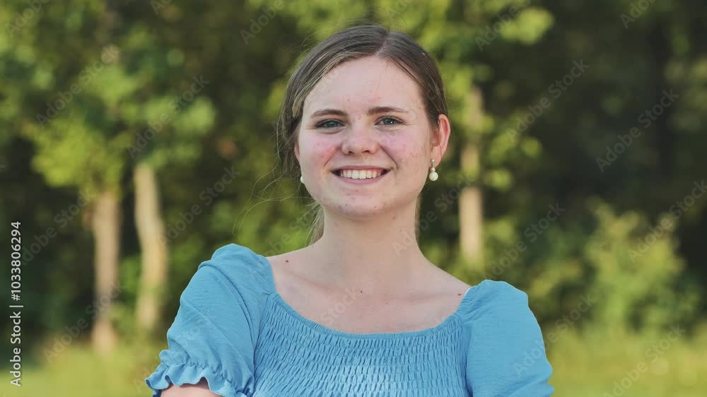 Young girl is smiling outdoors on a summer day, wearing a blue dress and enjoying the warm weather. Young girl is smiling outdoors on a summer day, wearing a blue dress and enjoying the warm weather.