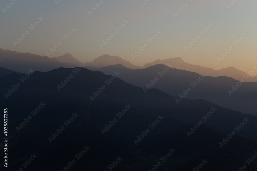 A serene view of distant mountain ranges at dusk with a soft gradient sky. A serene view of distant mountain ranges at dusk with a soft gradient sky.