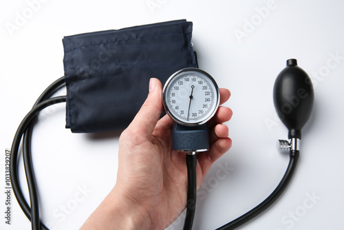 Woman with blood pressure measuring device on light background, top view