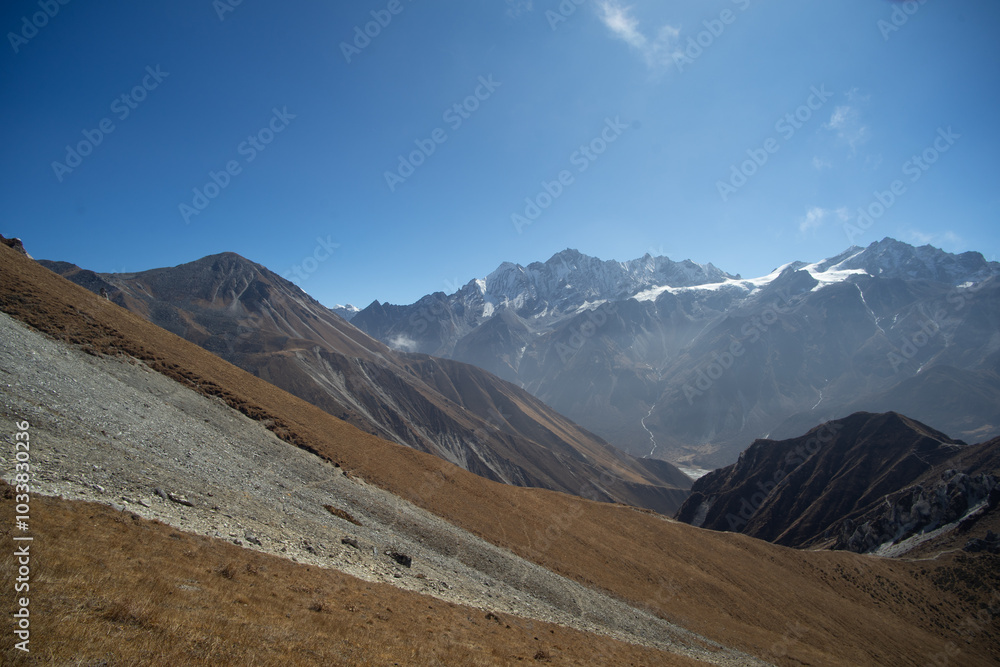 A breathtaking view of a mountain range with dry grassy slopes under a clear blue sky. A breathtaking view of a mountain range with dry grassy slopes under a clear blue sky.
