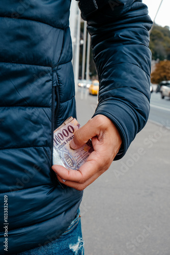 man takes out or puts some forint notes into his pocket