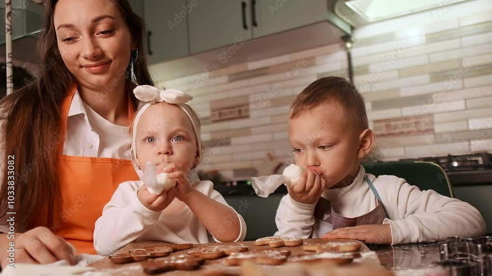 Top view of a mother and children decorating gingerbread cookies with icing, enjoying quality family time on winter evenings. Top view of a mother and children decorating gingerbread cookies with icing, enjoying quality family time on winter evenings.