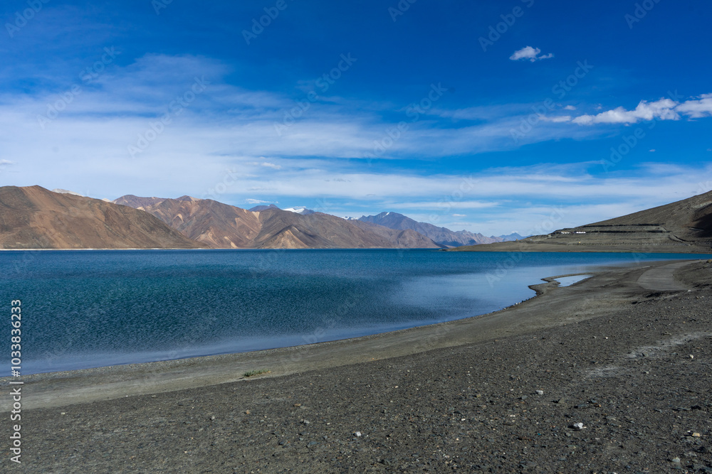Serene lake with mountainous backdrop under a clear blue sky Serene lake with mountainous backdrop under a clear blue sky