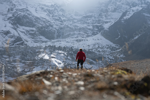 Bild auf Leinwand A lone hiker trekking towards the snow-capped mountain peaks.