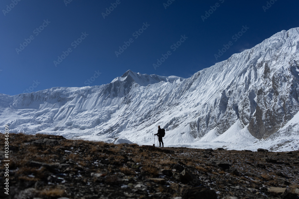 A hiker stands in awe of the majestic, snowy mountain range under a clear blue sky. A hiker stands in awe of the majestic, snowy mountain range under a clear blue sky.