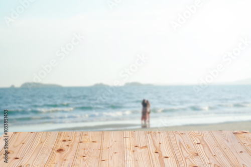 Wooden table with blurred beach background featuring a couple, ideal for holiday and love concepts