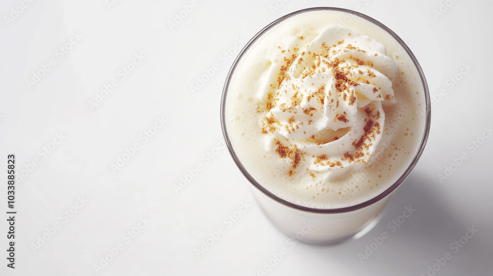 Creamy beverage topped with whipped cream and spices in a clear glass Creamy beverage topped with whipped cream and spices in a clear glass