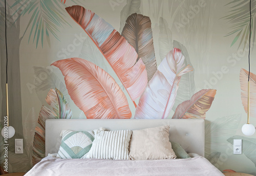 Modern interior of bedroom with comfortable bed with pillows and textured wallpaper od the wall with leaves pattern. Design house and cozy home.