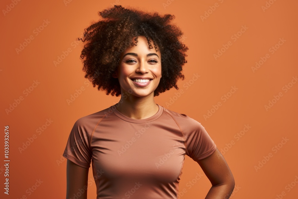 Portrait of a smiling afro-american woman in her 20s wearing a moisture-wicking running shirt on soft brown background Portrait of a smiling afro-american woman in her 20s wearing a moisture-wicking running shirt on soft brown background