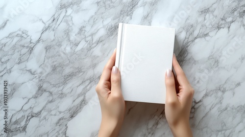 Photorealistic scene of a pair of hands gently holding a closed white book, The background is a high-resolution marble surface with subtle