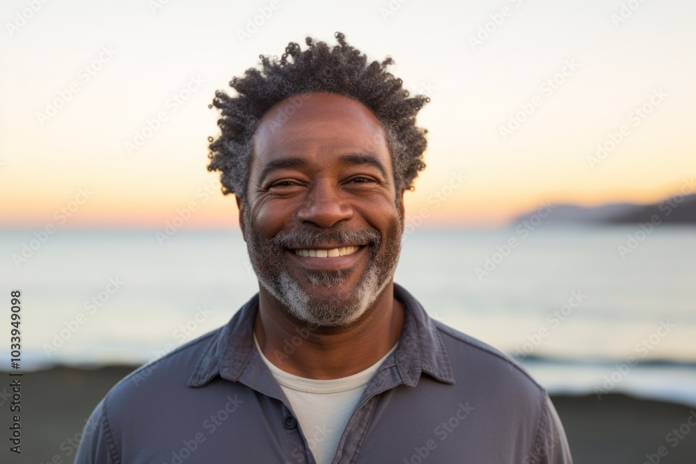 Portrait of a smiling afro-american man in his 50s sporting a long-sleeved thermal undershirt in stunning sunset beach background Portrait of a smiling afro-american man in his 50s sporting a long-sleeved thermal undershirt in stunning sunset beach background