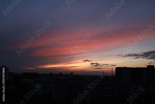 Beautiful sunset over a big city. The pink sunset illuminates the thick clouds. Multicolored sunset.