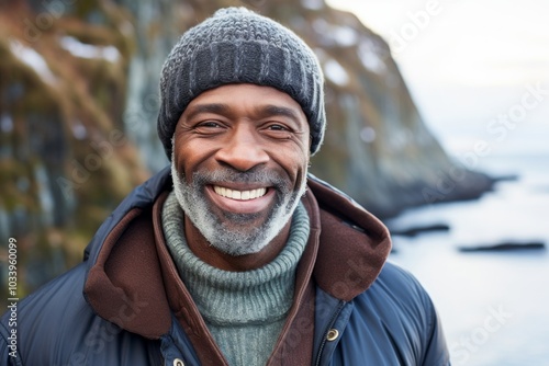 Portrait of a smiling afro-american man in his 50s sporting a trendy beanie on rocky shoreline background