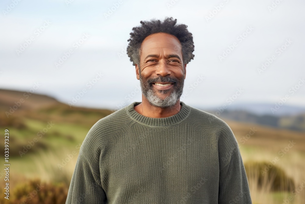 Portrait of a satisfied afro-american man in his 50s wearing a cozy sweater while standing against serene dune landscape background Portrait of a satisfied afro-american man in his 50s wearing a cozy sweater while standing against serene dune landscape background