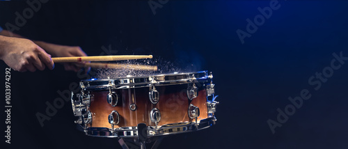 Foto Drum sticks hitting snare drum with splashing water on black background