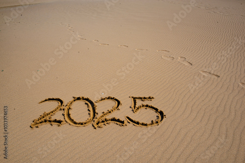 2025 text handwriting on the sand in a beach with empty space at the top -gre...